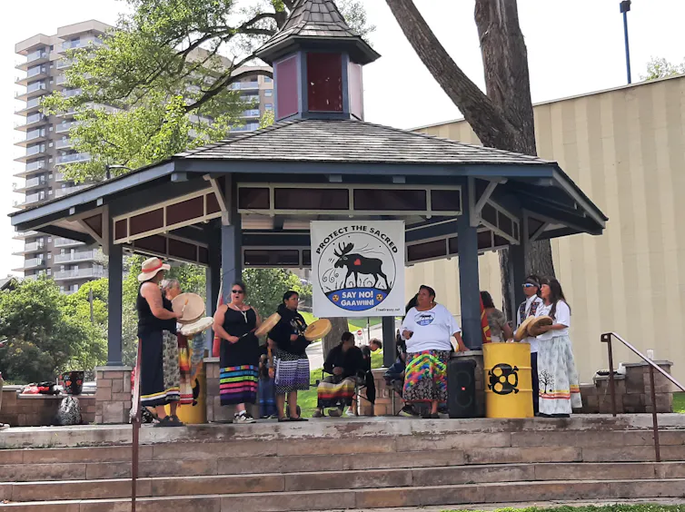 women in a pavilion sing and play drums