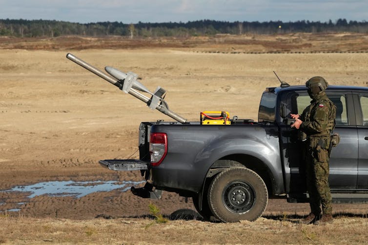 a small rocket sits on a pole protruding from the bed of a pickup truck