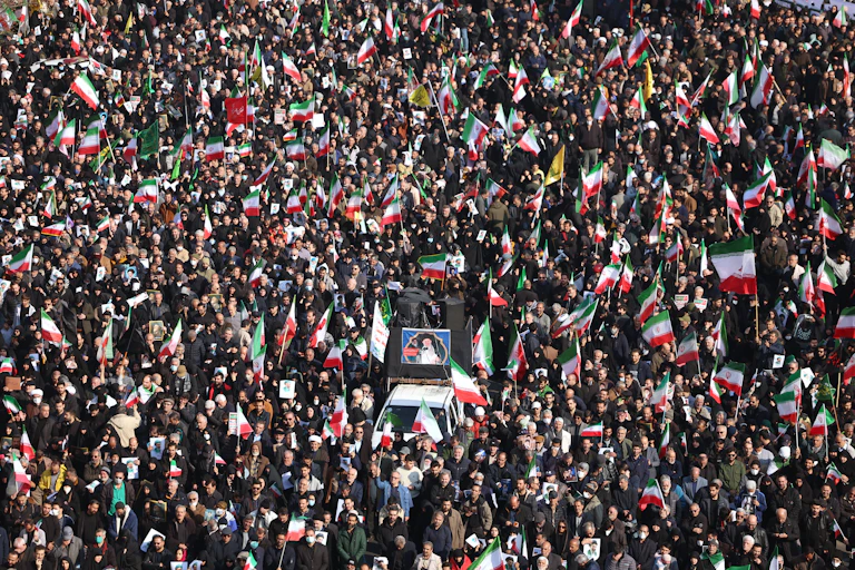 Hundreds of people gathered, holding green, white and red flags and carrying a large portrait.