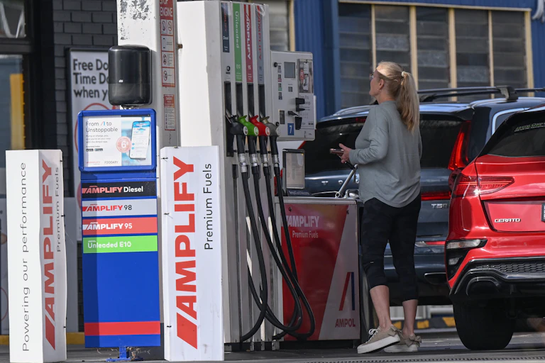 woman looks at price of petrol on petrol pump.
