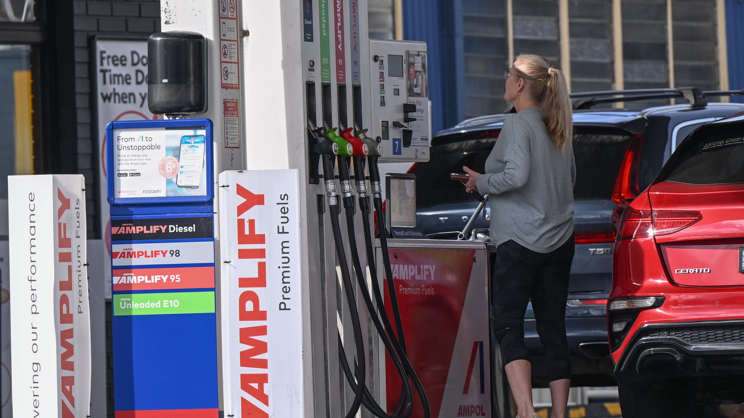 woman looks at price of petrol on petrol pump.