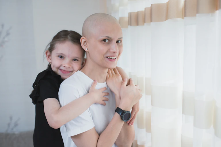 Smiling female cancer patient, with her young daughter hugging her.