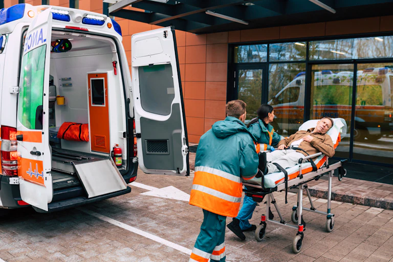 Personal d'ambulància entrant una llitera amb rodes amb un pacient a les portes d'un hospital.