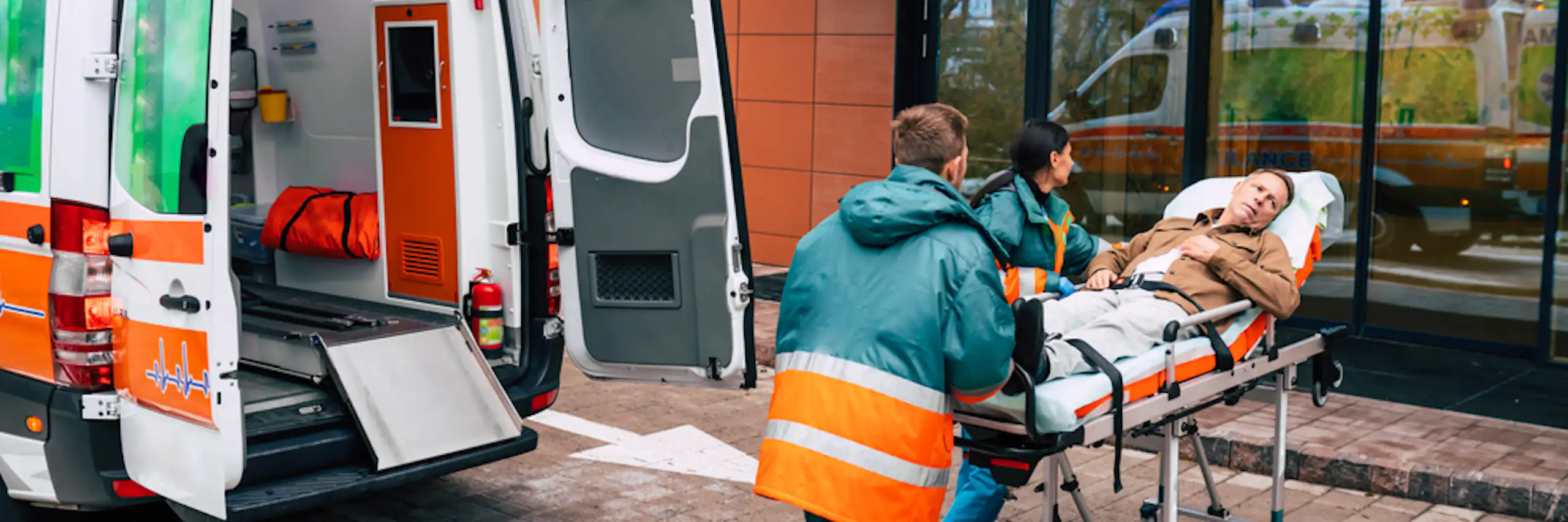 Personal d'ambulància entrant una llitera amb rodes amb un pacient a les portes d'un hospital.