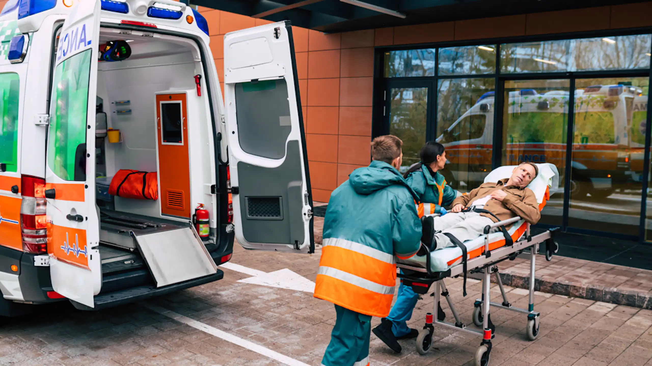 Personal d'ambulància entrant una llitera amb rodes amb un pacient a les portes d'un hospital.
