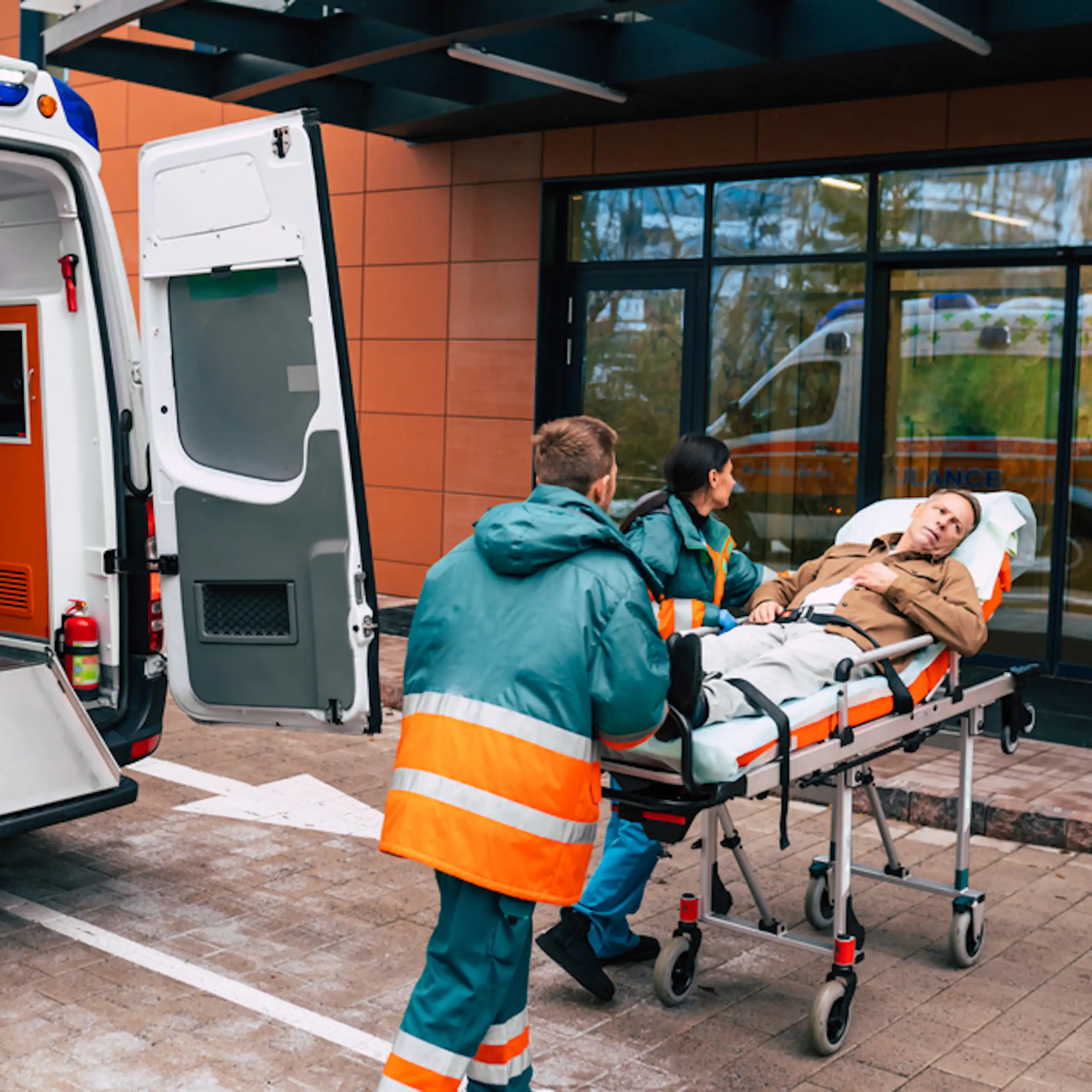 Personal d'ambulància entrant una llitera amb rodes amb un pacient a les portes d'un hospital.