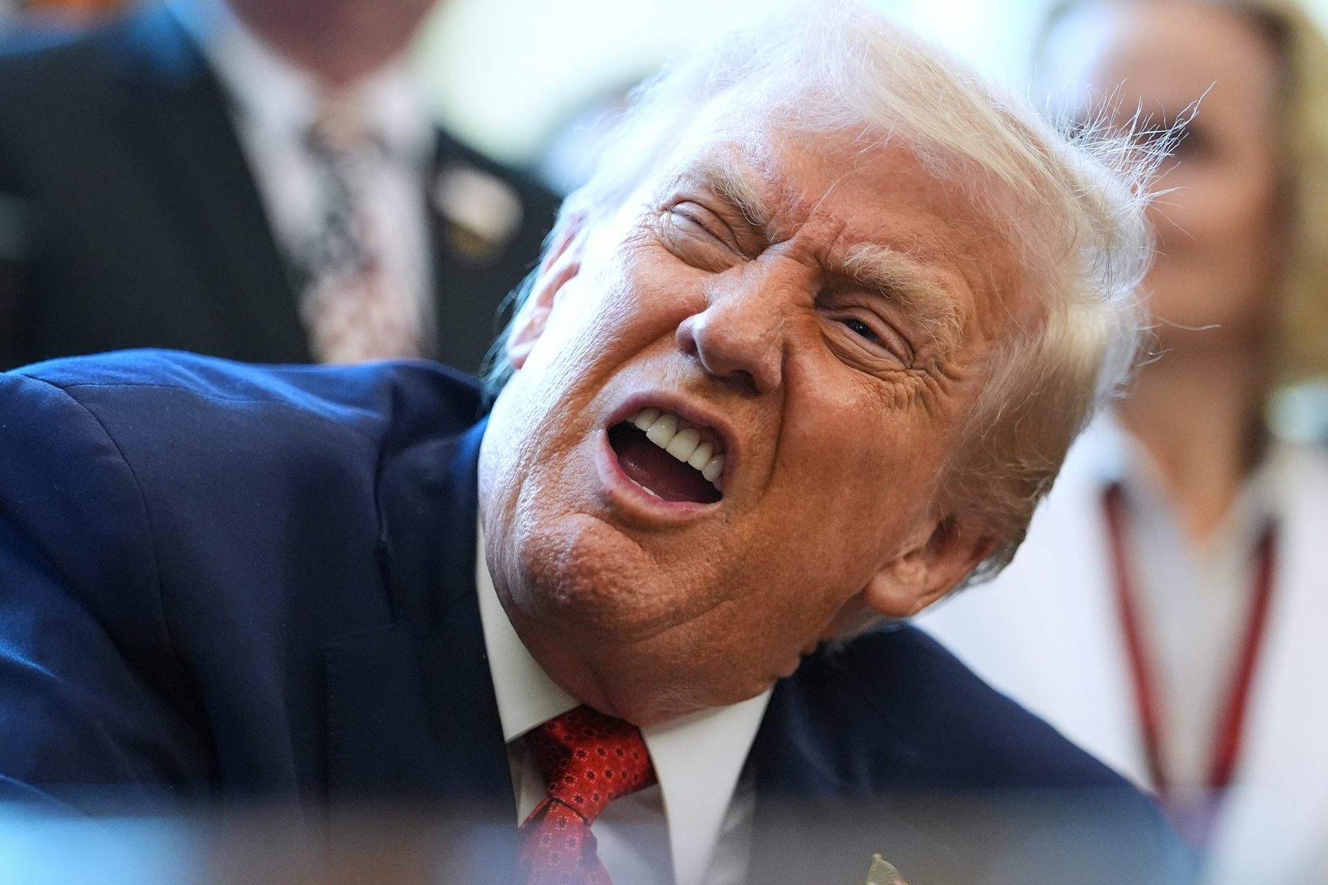 Un anciano de piel naranja y suave cabello blanco amarillento hace una mueca.