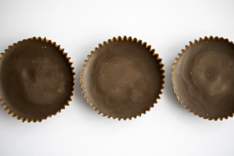 Three chocolate peanut butter cup candies in a row on white background