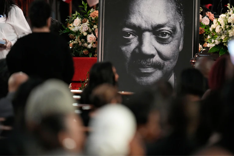Portrait of Jesse Jackson's face at his memorial service, attendees blurred in the foreground