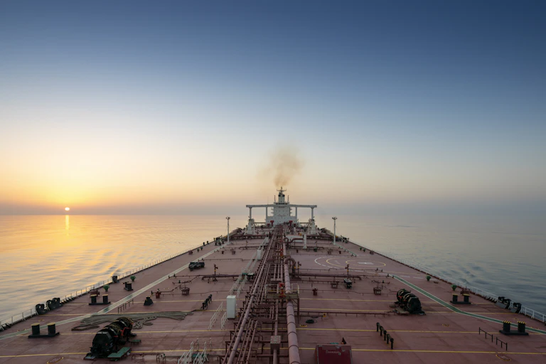 view along the deck of a oil super tanker at sea with sunset in the background