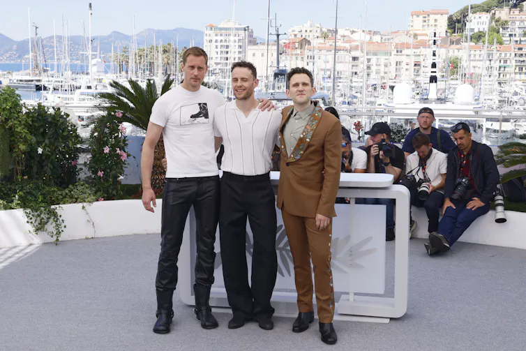 No más caricaturas raras: cómo 'Pillion' está reescribiendo el cine BDSM 3 Tres hombres abrazados mientras son fotografiados por muchos fotógrafos.