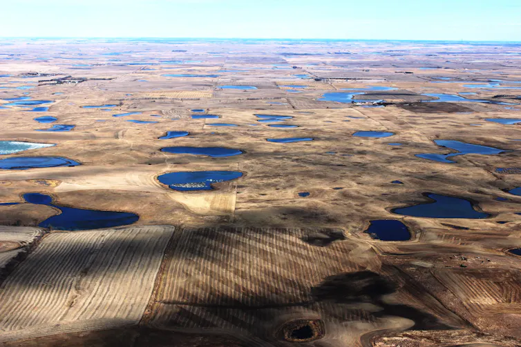 bodies of water dot a landscape of brown farm fields