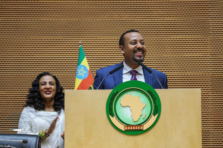 A man standing at a podium and smiling while a woman claps behind him