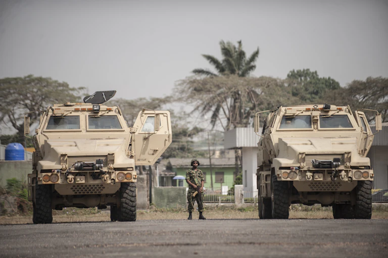 A soldier standing in between armoured vehicles