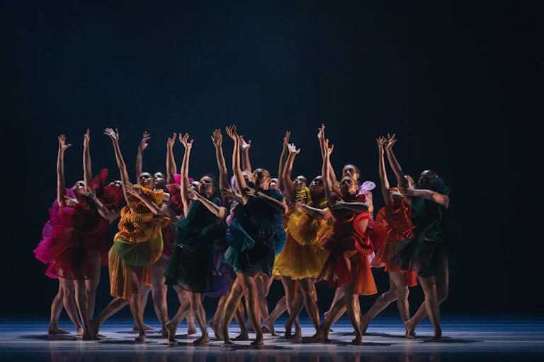 A cast of dancers in colourful dresses.