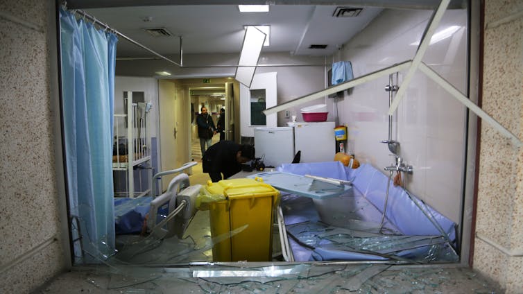 Shattered glass surrounds a damaged hospital ward.