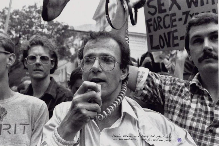 a man with glasses talking into a megaphone at a rally