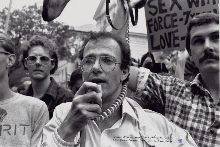 a man with glasses talking into a megaphone at a rally