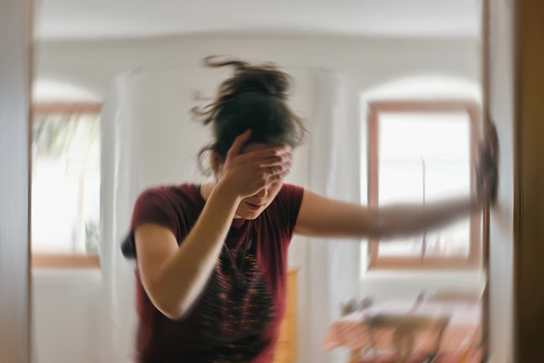 Young woman holding her head, looking dizzy.