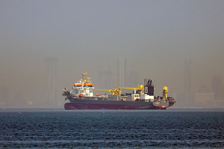 A vessel anchored in the Persian Gulf with Dubai's skyline in the background.