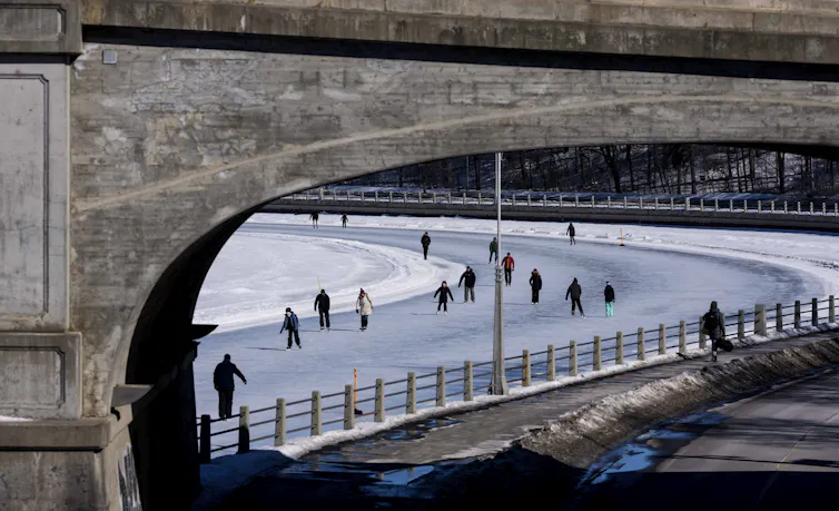 La gente patina en el canal congelado debajo del puente.