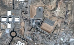 An overhead view shows buildings, roads and fences.