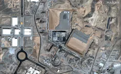 An overhead view shows buildings, roads and fences.