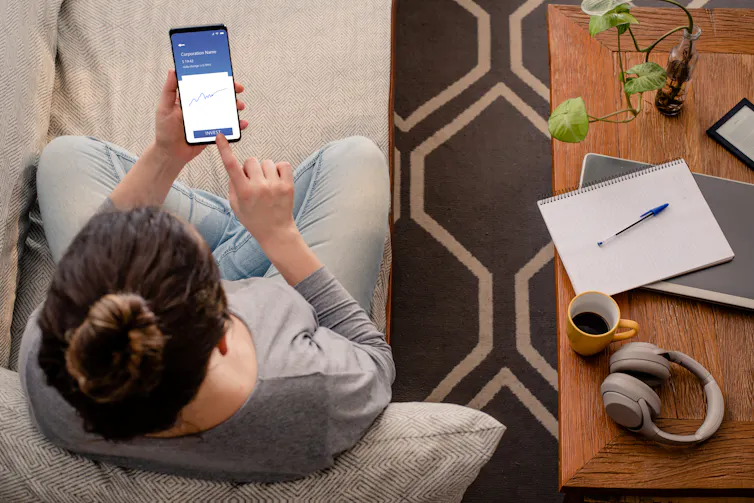aerial shot of a woman looking at an investment app on her phone.
