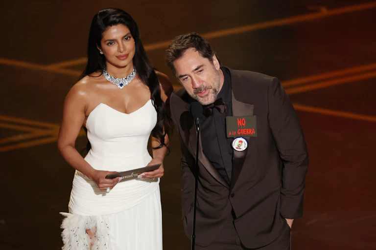 Javier Bardem wearing his protest lapel, on stage with Priyanka Chopra.