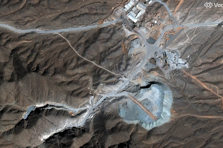 An overhead view of a rugged landscape with gravel roads and metal buildings.