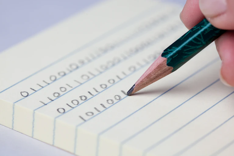 A hand holding a pencil and writing binary code on lined paper.