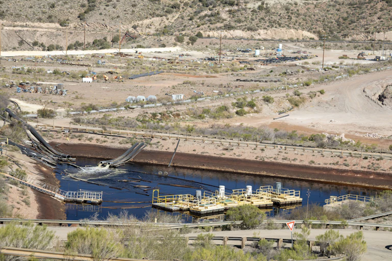 A wide view of a landscape with trucks, large pipes and roads.