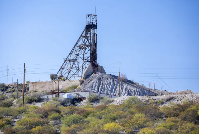 A large metal structure sits near a pile of rock.