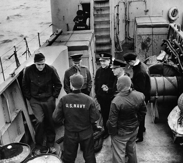A group of men dressed for cold weather standing on a boat.