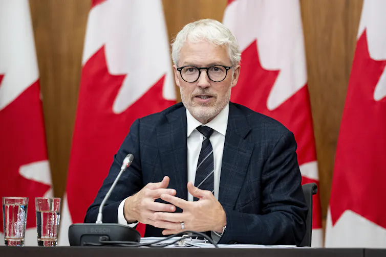 El comisionado de Privacidad de Canadá, Philippe Dufresne, habla frente a la bandera canadiense.