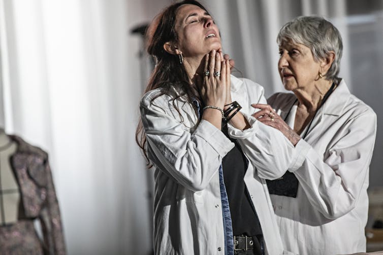 Two women on stage in white lab coats.