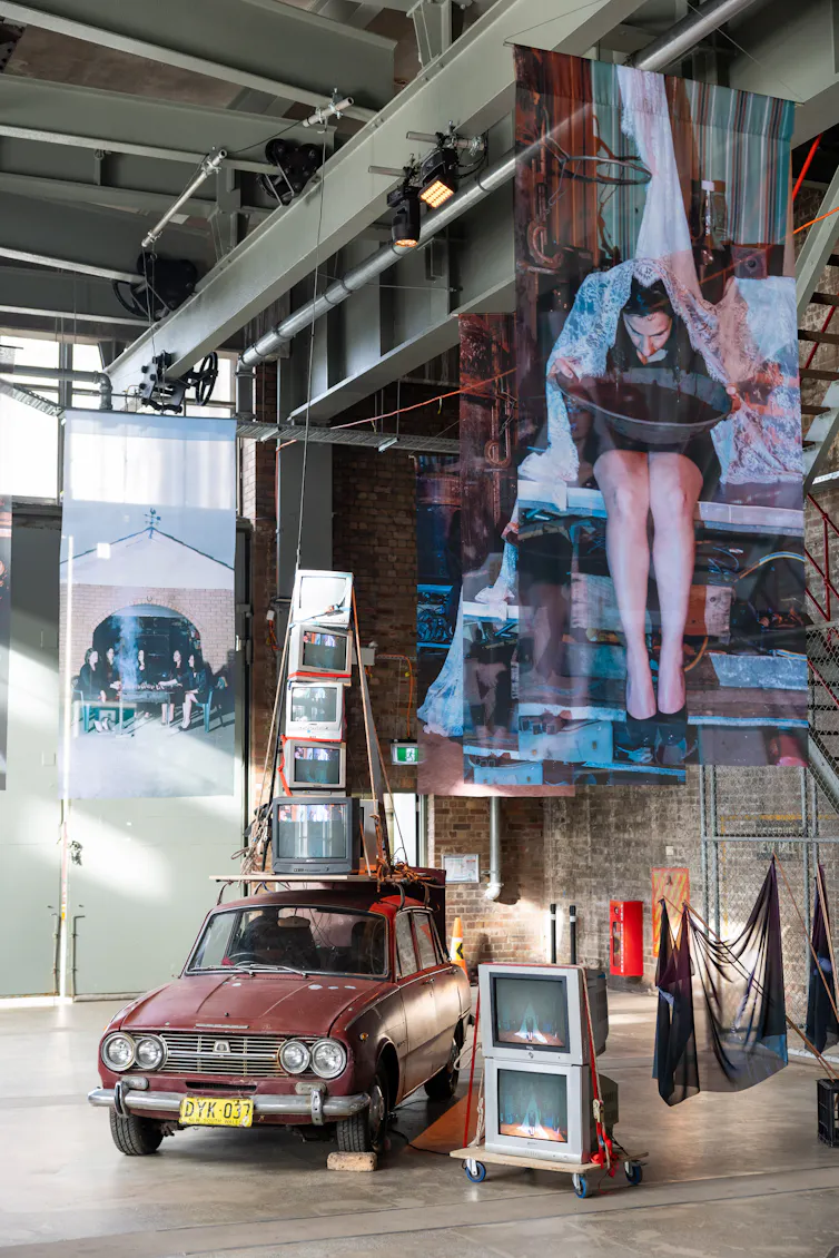 A car, some TVs, large hanging photos.