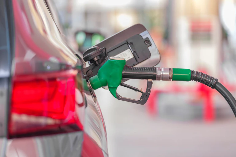 Petrol pump nozzle in car tank at petrol station