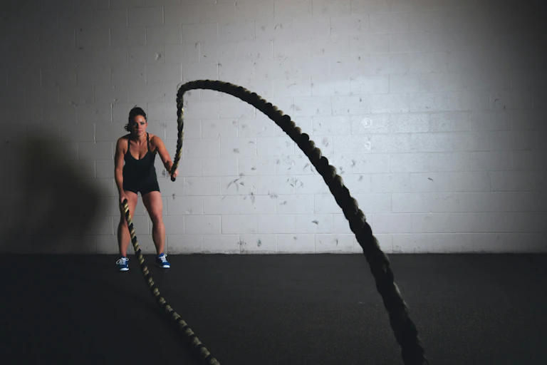 A woman lifting thick ropes in a gym.