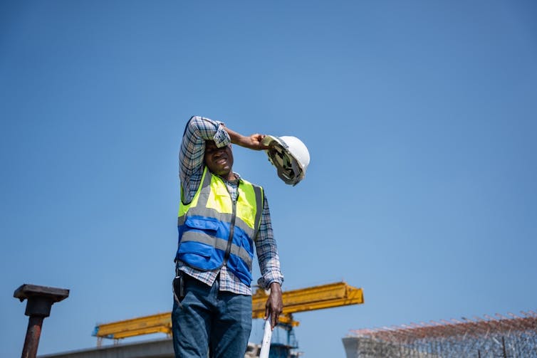 A labourer wiping the sweat from his brow.