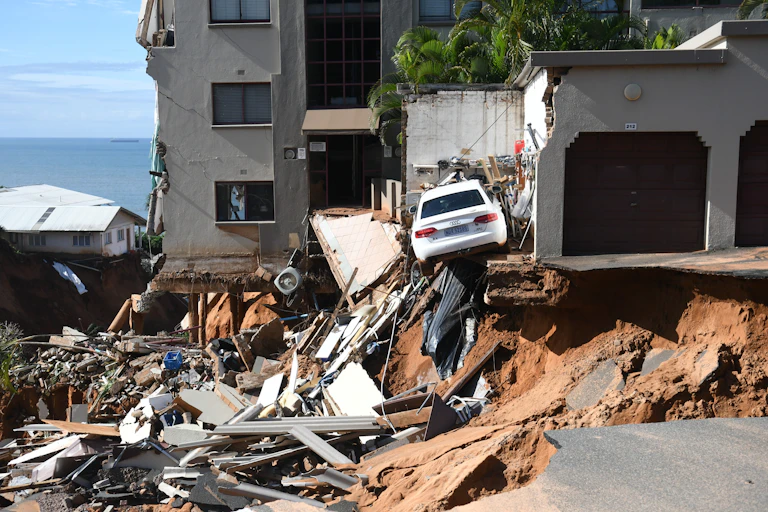 An urban four-storey building where the bottom storey and a parking lot have been washed away by floods