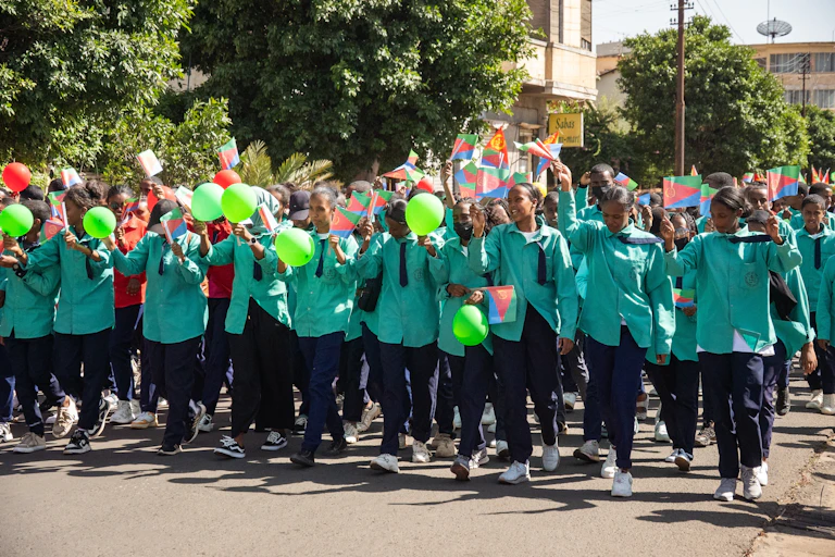 Students in green with flags and balloons