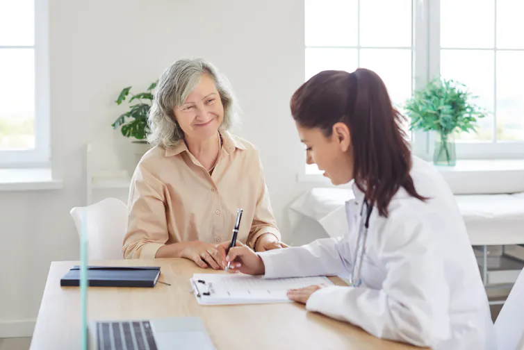A smiling woman attending a doctor's appointment alone.
