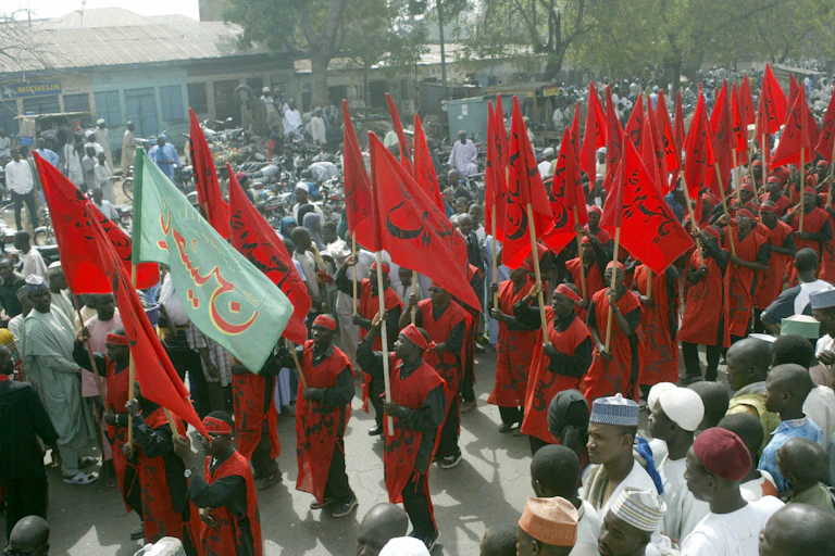 People with red clothing and red flags, gathered in a crowd outdoors