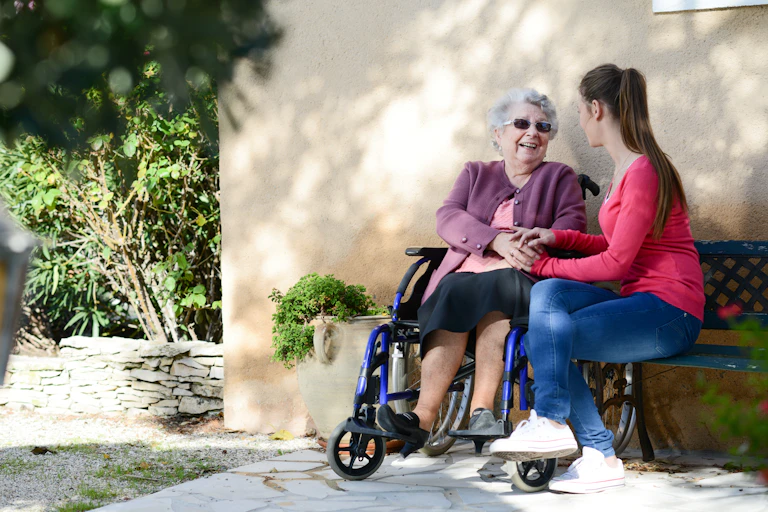 Una joven con una anciana sentadas en un banco