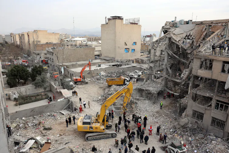 Iranian rescue workers work among the rubble of damaged residential buildings in central Tehran.