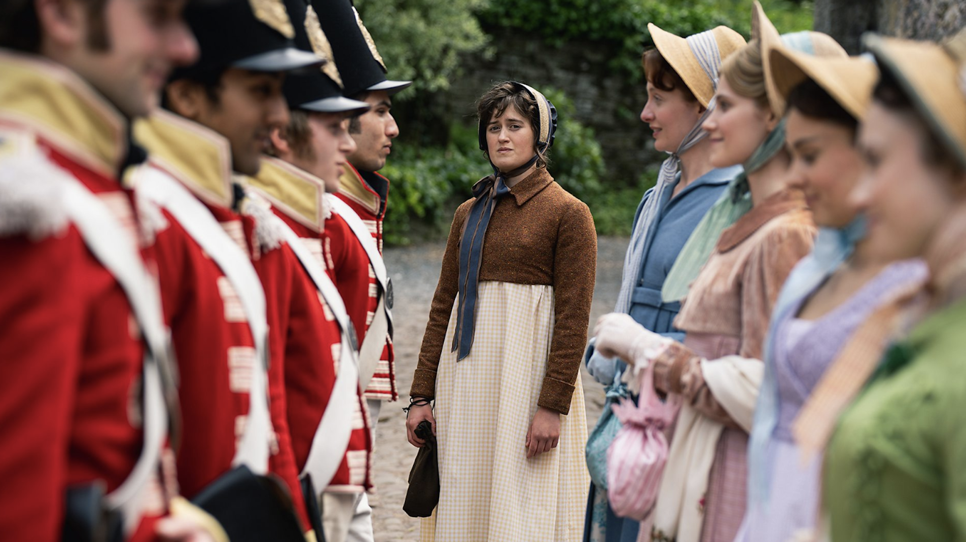 A group of early 19th=century women in Regency dress standing opposite a line of red-uniformed soldiers.
