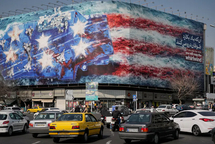 Cars drive by a building with a picture of a U.S. flag and air carrier on it.