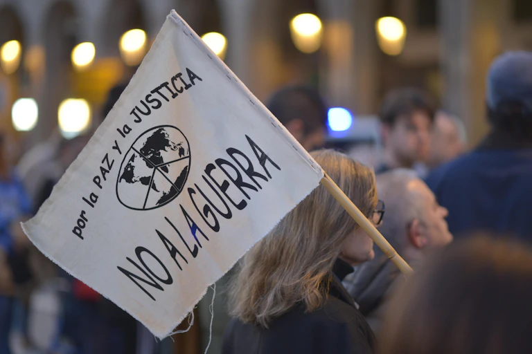 A woman at a demonstration holding a placard that reads ‘For peace and justice. No to war’ in Spanish.