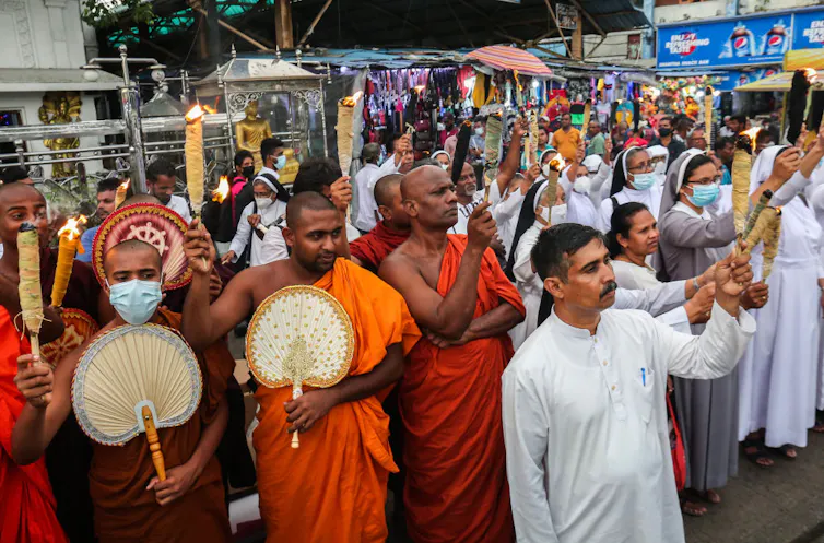 Rising up right through Sri Lanka’s civil battle taught me that obtaining in conjunction with other people throughout divides is a distinctive feature we will be informed 1 A crowd of people on the street includes men in orange robes, nuns in white dresses, and a man in a long white tunic.